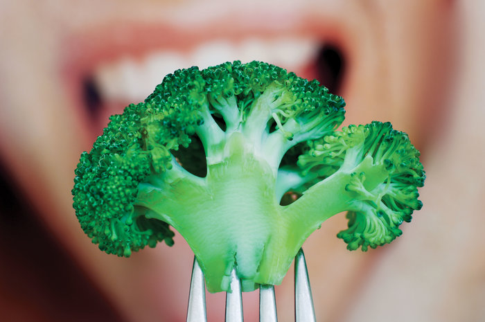 woman eating broccoli floret with fork