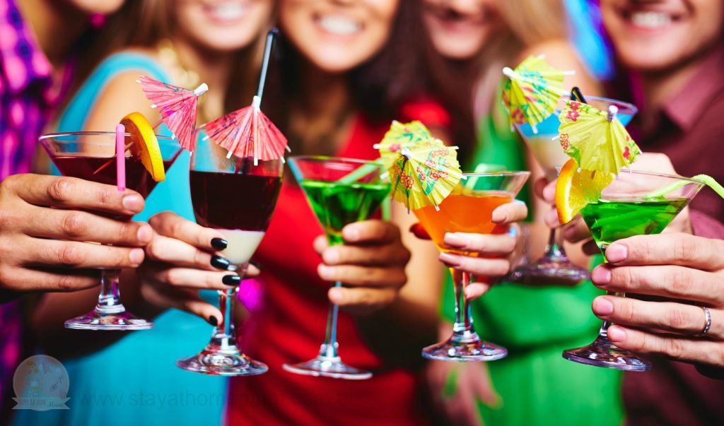 Glasses with cocktails held by happy friends at party