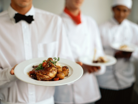 two chefs and a waiter standing in a row