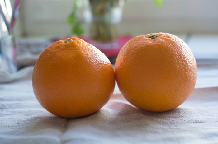 Two oranges side by side on linen towel closeup